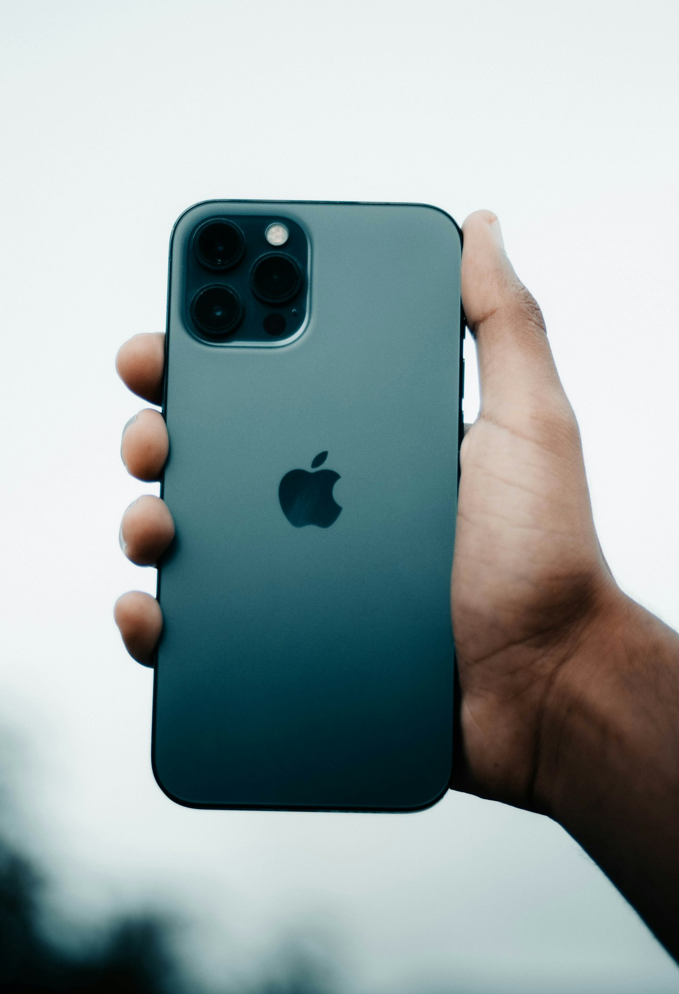 手持iPhone背面,展示摄像头与Apple标志